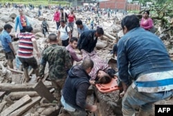 A handout picture released by the Colombian Army press office shows people helping to carry a woman after mudslides following heavy rains, in Mocoa, Putumayo, on April 1, 2017.