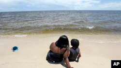 Tracey Gasper, left, and her son, Chase, 6, from Donaldsonville, La., sit in the sands of Biloxi Beach in Biloxi, Miss., May 26, 2018, as Subtropical Storm Alberto slowly makes its way through the Gulf of Mexico. The storm is threatening to bring heavy ra