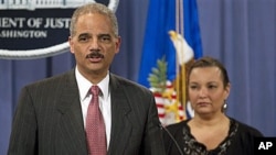 US Attorney General Eric Holder, accompanied by Environmental Protection Agency Administrator Lisa Jackson, gestures during a news conference to announce a civil lawsuit against nine defendants for the Deepwater Horizon oil spill at the Justice Department