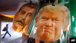 FILE - Facemasks depicting former Soviet dictator Josef Stalin and U.S President-elect Donald Trump hang on sale hours before Trump is to be sworn in as president of the United States, at a souvenir street shop in St. Petersburg, Russia, Jan. 20, 2017.