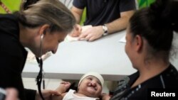 A doctor examines a cleft-lipped baby during an evaluation provided by Operation Smile volunteers at San Felipe hospital in Tegucigalpa, November 14, 2012. 