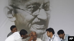 Veteran Indian social activist Anna Hazare (C) is examined by a team of doctors in front of a portrait of Mahatma Gandhi on the eighth day of his fasting at Ramlila grounds in New Delhi, Aug. 23, 2011.