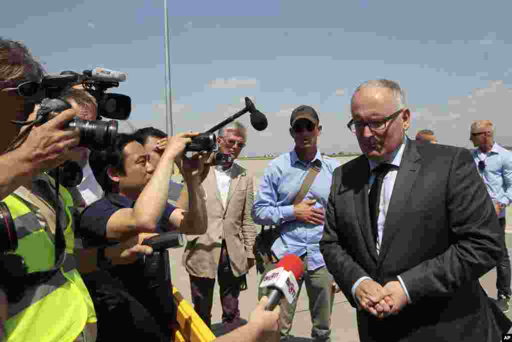 Netherlands Foreign Minister Frans Timmermans (right) speaks to the media while a Dutch military cargo plane with bodies of some of the passengers of the downed Malaysia Airlines jetliner leaves Ukraine for the Netherlands, July 25, 2014.