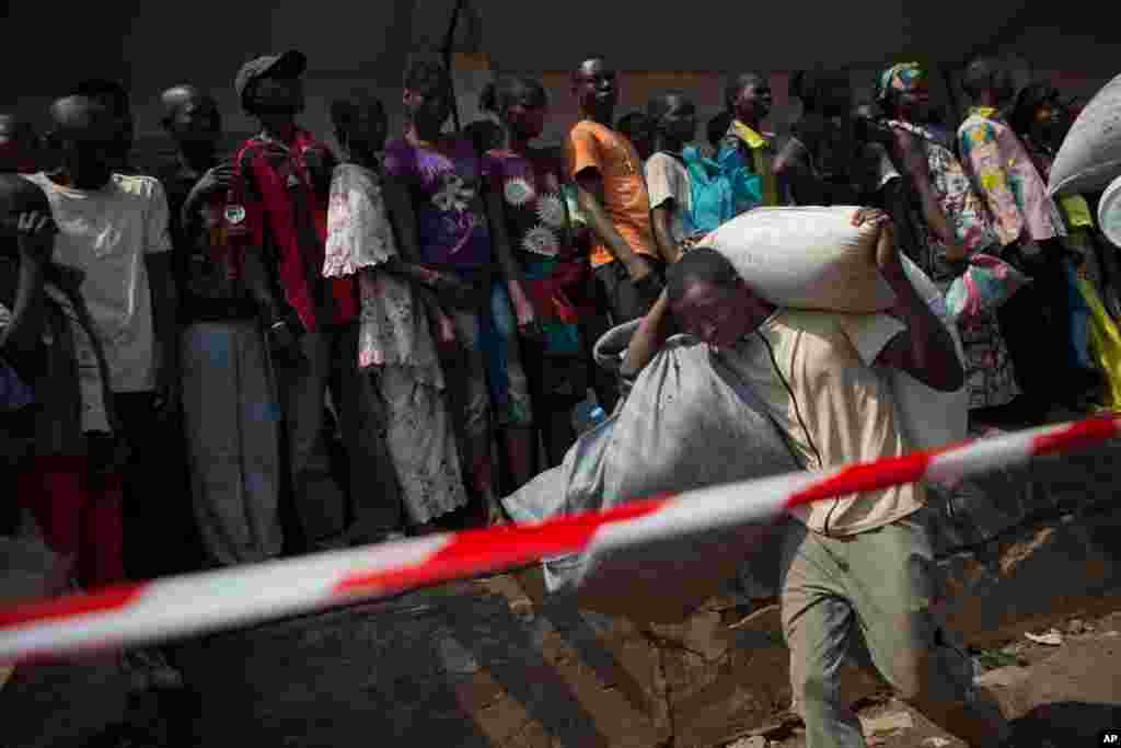 A man carries away food supplies from an aid distribution point set up inside a makeshift camp at Mpoko Airport in Bangui, Jan. 7, 2014. 