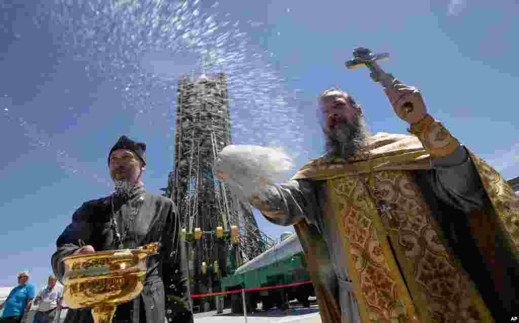 An Orthodox priest conducts a blessing service in front of the Soyuz FG rocket at the Russian leased Baikonur Cosmodrome, Kazakhstan.