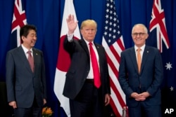 President Donald Trump, accompanied by Japanese Prime Minister Shinzo Abe, left, and Australian Prime Minister Malcolm Turnbull, right, waves to reporters at a meeting during the ASEAN Summit at the Sofitel Philippine Plaza, Nov. 13, 2017.