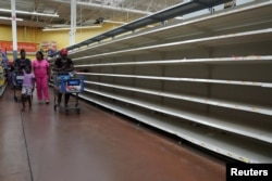 People walk past empty shelves where bread is normally sold in a Walmart store in advance of Hurricane Irma's expected arrival in North Miami Beach, Florida, Sept. 7, 2017.