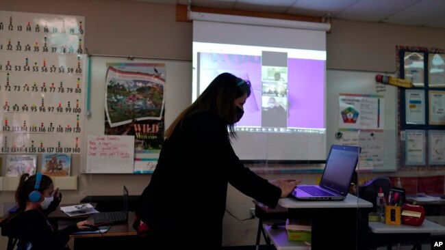 Wylona Rogers teaches students attending a class in-person as well as students attending virtually at Driggers Elementary School, Monday, Feb. 8, 2021, in San Antonio. After seeing two academic years thrown off course by the pandemic, school leaders around the ｃountry are planning for the possibility of more distance learning next fall at the start of yet another school year. (AP Photo/Eric Gay)