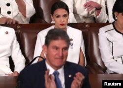 Rep. Alexandria Ocasio-Cortez (D-NY) (R) remains in her seat as Senator Joe Manchin (D-WV) stands and applauds as President Donald Trump delivers his State of the Union address to a joint session of Congress at the U.S. Capitol in Washington, Feb. 5, 2019.