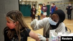 Ione Thompson, de 10 años, recibe la primera dosis de la vacuna contra la enfermedad del coronavirus Pfizer-BioNTech (COVID-19) de Iman Yunis de la farmacia Othello Station, durante una clínica de día escolar de las Escuelas Públicas de Seattle. 