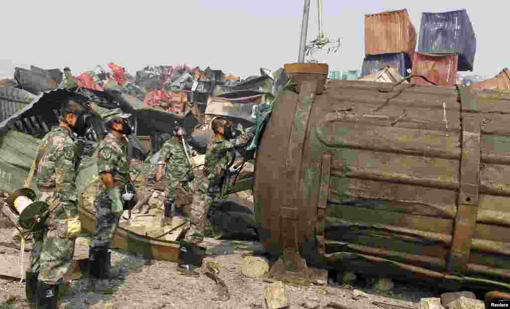 Soldiers of the People&#39;s Liberation Army&#39;s anti-chemical warfare corps, wearing gas masks, examine a container at the site of explosions at Binhai new district in Tianjin, China.