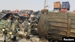 Soldiers of the People's Liberation Army's anti-chemical warfare corps, wearing gas masks, examine a container at the site of last week's explosions at Binhai new district in Tianjin, China, Aug. 16, 2015. 