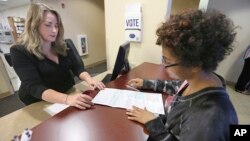 Sabine Kamagou, 19, right, gets help filling out a voter registration form from Cyndi Morrison, a worker in the Sacramento County registrar's office, in Sacramento, Calif., Oct. 22, 2018. 