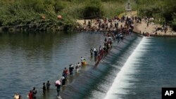 Migran Haiti menyeberangi bendungan dari Meksiko untuk memasuki Del Rio, Texas, Amerika Serikat, Sabtu, 18 September 2021. (AP Photo/Eric Gay)