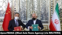 伊朗德黑兰，伊朗外长扎里夫和中国外长王毅在25年合作协议的签字仪式上互碰手肘（2021年3月27日）。