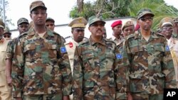 FILE - Somalia's Defense Minister Abdirashid Abdulahi Mohamed, left, watches a military unit alongside President Mohamed Abdullahi Mohamed, center, and Somali Prime Minister Hassan Ali Khayre, right, during celebrations marking the 57th anniversary since Somali military was founded, in Mogadishu, April 12, 2017.