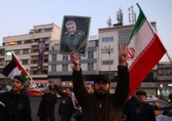 A man holds a picture of late Iranian Major-General Qassem Soleimani, as people celebrate in the street after Iran launched missiles at U.S.-led forces in Iraq, in Tehran, Iran January 8, 2020. Nazanin Tabatabaee/WANA (West Asia News Agency)