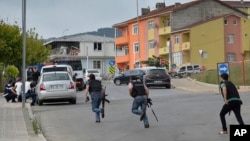 Turkish police officers run for cover during a gunfight near the site of an overnight explosion at a police station in Istanbul's Sultanbeyli neighborhood, Aug. 10, 2015. 