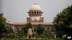 FILE - A gardener works in the lawns of the Supreme Court in New Delhi, India, Aug. 22, 2017.