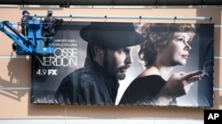 Workers put up a poster for the upcoming FX limited series "Fosse/Verdon" near the entrance to Fox Studios, March 19, 2019, in Los Angeles.