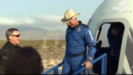 This photo provided by Blue Origin, Jeff Bezos, founder of Amazon and space tourism company Blue Origin, exits the Blue Origin's New Shepard capsule after it parachuted safely down to the launch area. (Blue Origin via AP)