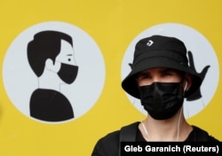 FILE - A man wearing a protective face mask amid the outbreak of the coronavirus disease (COVID-19) stands in front of a social poster in central Kyiv, Ukraine July 30, 2020. (REUTERS/Gleb Garanich/File)
