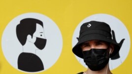 FILE - A man wearing a protective face mask amid the outbreak of the coronavirus disease (COVID-19) stands in front of a social poster in central Kyiv, Ukraine July 30, 2020. (REUTERS/Gleb Garanich/File)