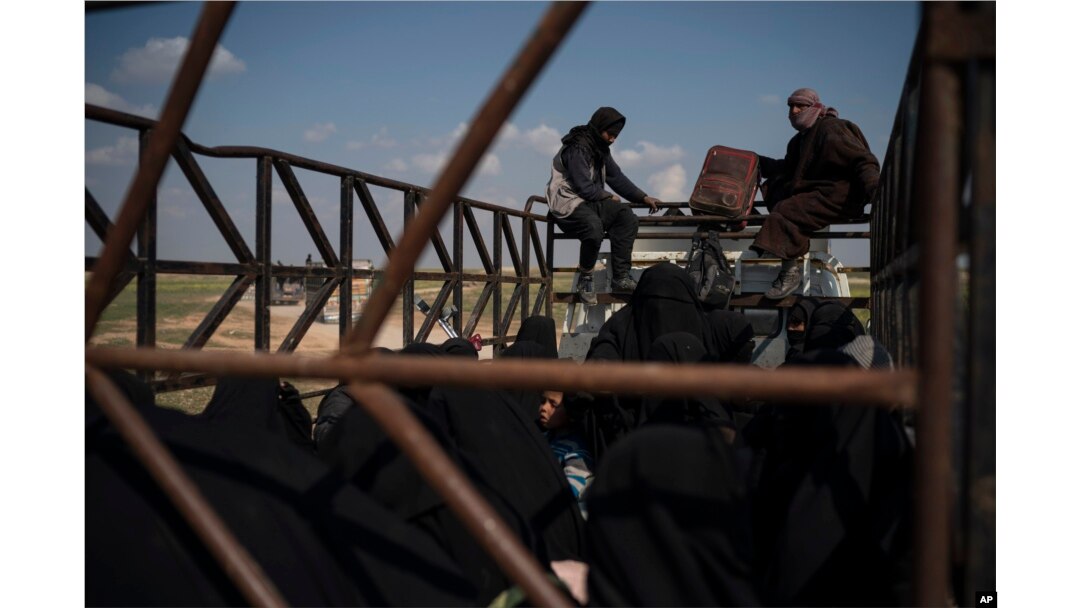 Men, women and children ride in the back of a truck in a convoy evacuating hundreds out of the last territory held by Islamic State militants in Baghuz, eastern Syria, Feb. 22, 2019. Small trucks carrying disheveled men, women and children left the Islamic State group's last pocket of territory in eastern Syria in an escorted convoy on Friday, hours after coalition airstrikes meant to pressure the militants targeted the area on the banks of the Euphrates River.