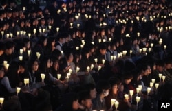 FILE - High school students hold candles to pay their respects to the victims of the sunken ferry Sewol during a ceremony on the eve of the second anniversary of the ferry sinking in Ansan, South Korea, April 15, 2016.