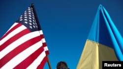 Seorang demonstran memegang bendera AS dan Ukraina selama demonstrasi "Berdiri dengan Ukraina" menentang invasi Rusia ke Ukraina, di depan Gedung Putih di Washington, AS, 28 Februari 2022. (Foto: REUTERS/Elizabeth Frantz)