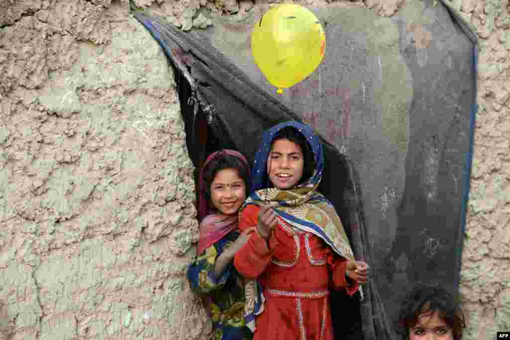 Internally displaced Afghan children play outside their temporary home at a refugee camp in Kabul, Afghanistan.