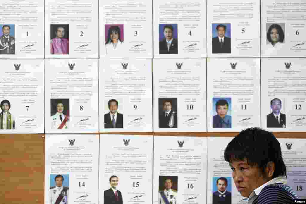 An official sits in front of a board with a list of candidates as she waits for voters at a polling station during a vote to elect a new Senate, in Bangkok, March 30, 2014.