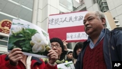 Protesters hold up pictures of jasmine flowers during a "Jasmine Revolution" protest outside the Chinese liaison office in Hong Kong, February 20, 2011.