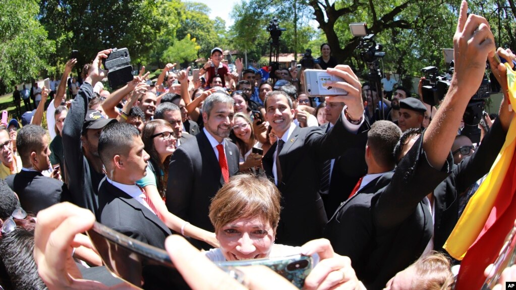 El presidente Mario Abdo Benítez (centro-izq.) y el presidente interino de Venezuela, Juan Guaidó posan con residentes venezolanos en Asunción, Paraguay el 1 de marzo de 2019. Foto Presidencia Paraguay vía AP.