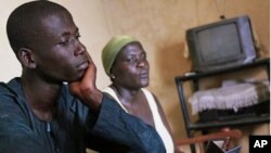 Adama Ouattara, 15, sits with his mother Eugenie Ouattara in the living room of their home, from where father and husband Adimou Ouattara was abducted on December 13 2010, in the Abobo district of Abidjan, Ivory Coast