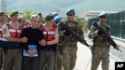 Paramilitary police officers and commandos escort alleged instigators of last summer's failed military coup, including former Air Force commander Gen. Akin Ozturk, front, before their trial at a courthouse near Ankara, Turkey, May 22, 2017.