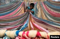 FILE - A boy separates starched sarees, a traditional Indian garment for women, left to dry on the roof of a cotton factory in the southern Indian city of Hyderabad, Nov. 30, 2012.