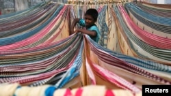 FILE - A boy separates starched sarees, a traditional Indian garment for women, left to dry on the roof of a cotton factory in the southern city of Hyderabad. Indian cricket legend Sachin Tendulkar, chess champion Viswanathan Anand and Bollywood stars took to Twitter this week to support a campaign against child labor, using their fame to draw greater attention to the issue, April 20, 2016.