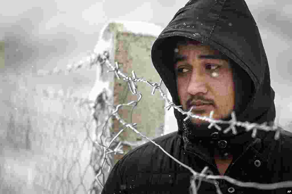 A migrant stands next to a fence during snowfall at the Lipa camp, outside Bihac, Bosnia. Very cold winter weather on has brought more suffering for hundreds of migrants who have been stuck for days in the camp.