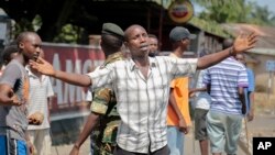 Un manifestant opposé à la candidature du président Pierre Nkurunziza pour un troisième mandat au Burundi discute avec des policiers, le 3 juin 2015, Bujumbura, Burundi.