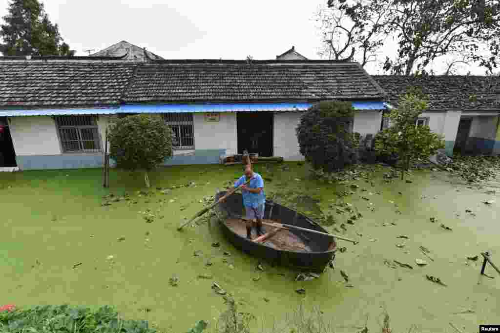 A man rows a boat near a flooded house in Hefei, Anhui Province, China.