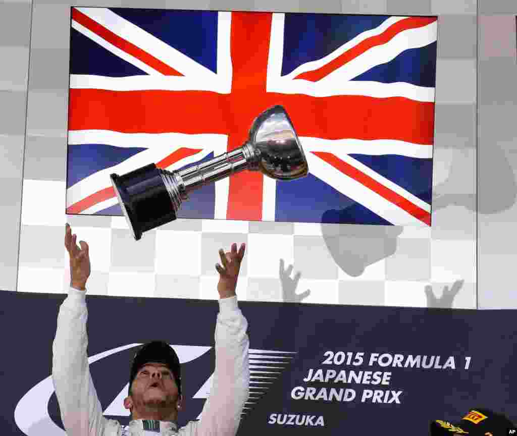 Mercedes driver Lewis Hamilton of Britain throws the trophy into the air on the podium after winning the Japanese Formula One Grand Prix at the Suzuka Circuit in Suzuka, central Japan.