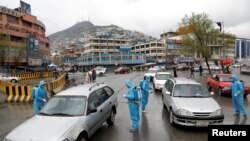 Para sukarelawan menyemprotkan disinfektan ke mobil-mobil di Kabul, Afghanistan, untuk menekan peneybaran virus corona di negara itu, 30 Maret 2020. (Foto: dok). 
