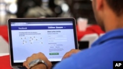 FILE - In this Jan. 4, 2018, file photo, a man demonstrates how he enters his Facebook page as he works on his computer in Brasilia, Brazil. Facebook is once again tweaking the formula it uses to decide what people see in their news feed.