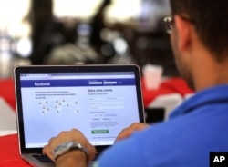 FILE - In this Jan. 4, 2018, photo, a man demonstrates how he enters his Facebook page as he works on his computer in Brasilia, Brazil.