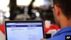 FILE - A user checks his Facebook page in Brasilia, Brazil, Jan. 4, 2018. Facebook connects 2.2 billion users and a host of communities that have sprung up on its network.