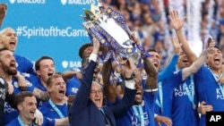 Leicester team manager Claudio Ranieri and Wes Morgan lift the trophy as Leicester City celebrates becoming the English Premier League soccer champions at King Power Stadium in Leicester, England, May 7, 2016.