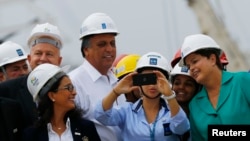 Brazil's president, Dilma Rousseff, prepares to take a photo with workers as IOC Coordination Commission head Nawal El Moutawakel (bottom L) watches during a visit to the Rio 2016 Olympic Park in Rio de Janeiro September 30, 2014.
