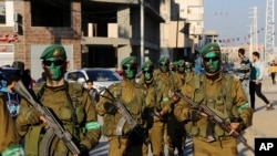 FILE - Masked militants from the Izzedine al-Qassam Brigades, a military wing of Hamas, paint their faces with green color while marching along the streets of Nusseirat refugee camp, Central Gaza Strip, Thursday, Jan. 19, 2017.