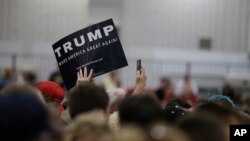 Seorang pendukung Donald Trump melambaikan papan bertuliskan nama kandidat calon presiden Partai Republik itu dalam kampanye di Indianapolis, Indiana (20/4). (AP/Darron Cummings)